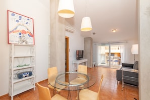 A modern living room with a glass table, wooden chairs, a sofa, and a TV on a stand. - Apartment with parking in downtown Begur (Begur)