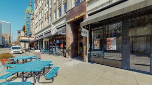 A street view with outdoor seating, a theater building, and a sign for 'IGS' on the corner. - Cozy 1-bedroom condo in downtown Louisville with free parking and gym access (Louisville)