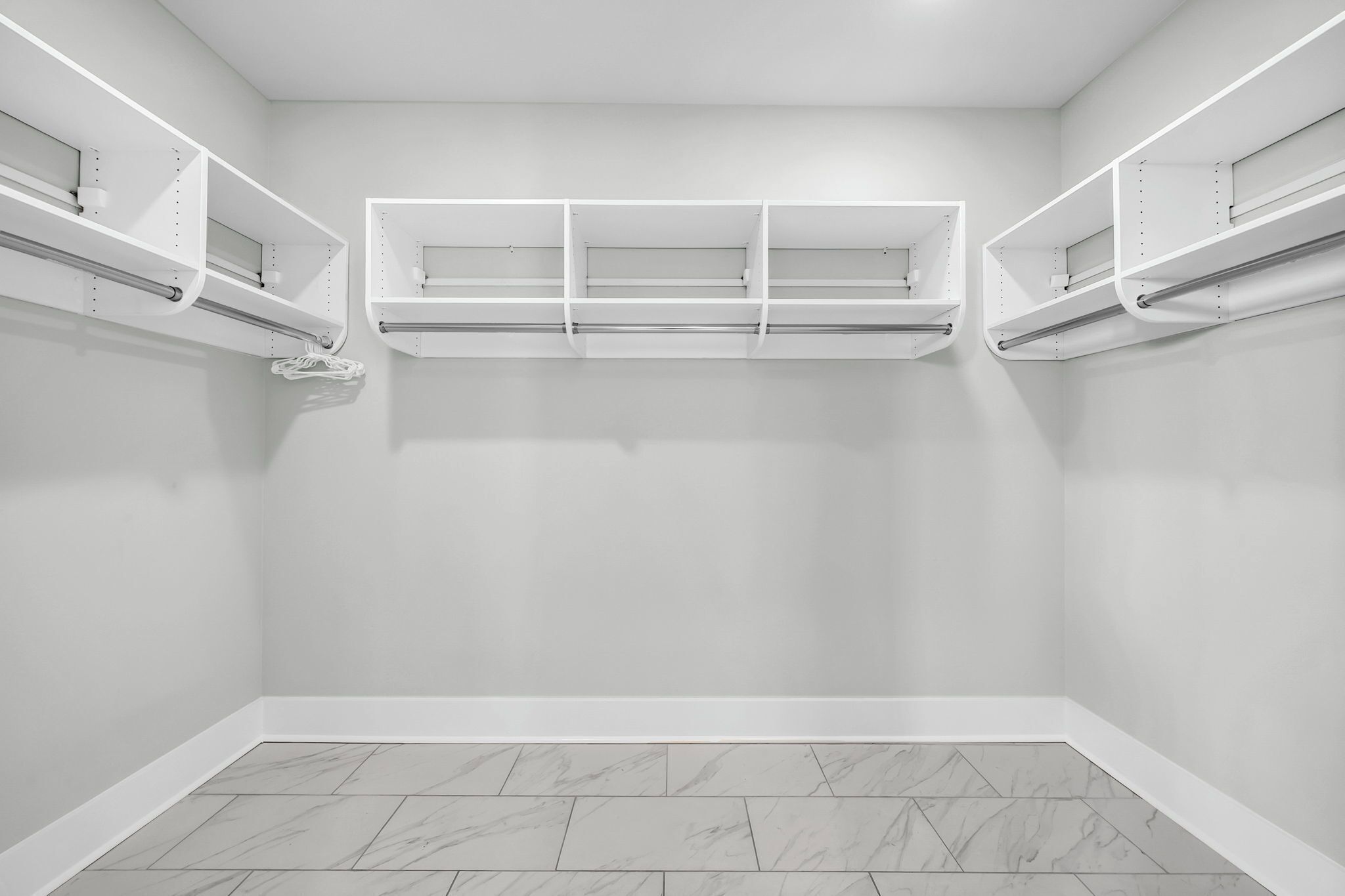 Una habitación con paredes blancas, suelo de baldosas y estanterías empotradas.