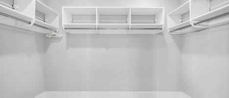 Una habitación con paredes blancas, suelo de baldosas y estanterías empotradas.
