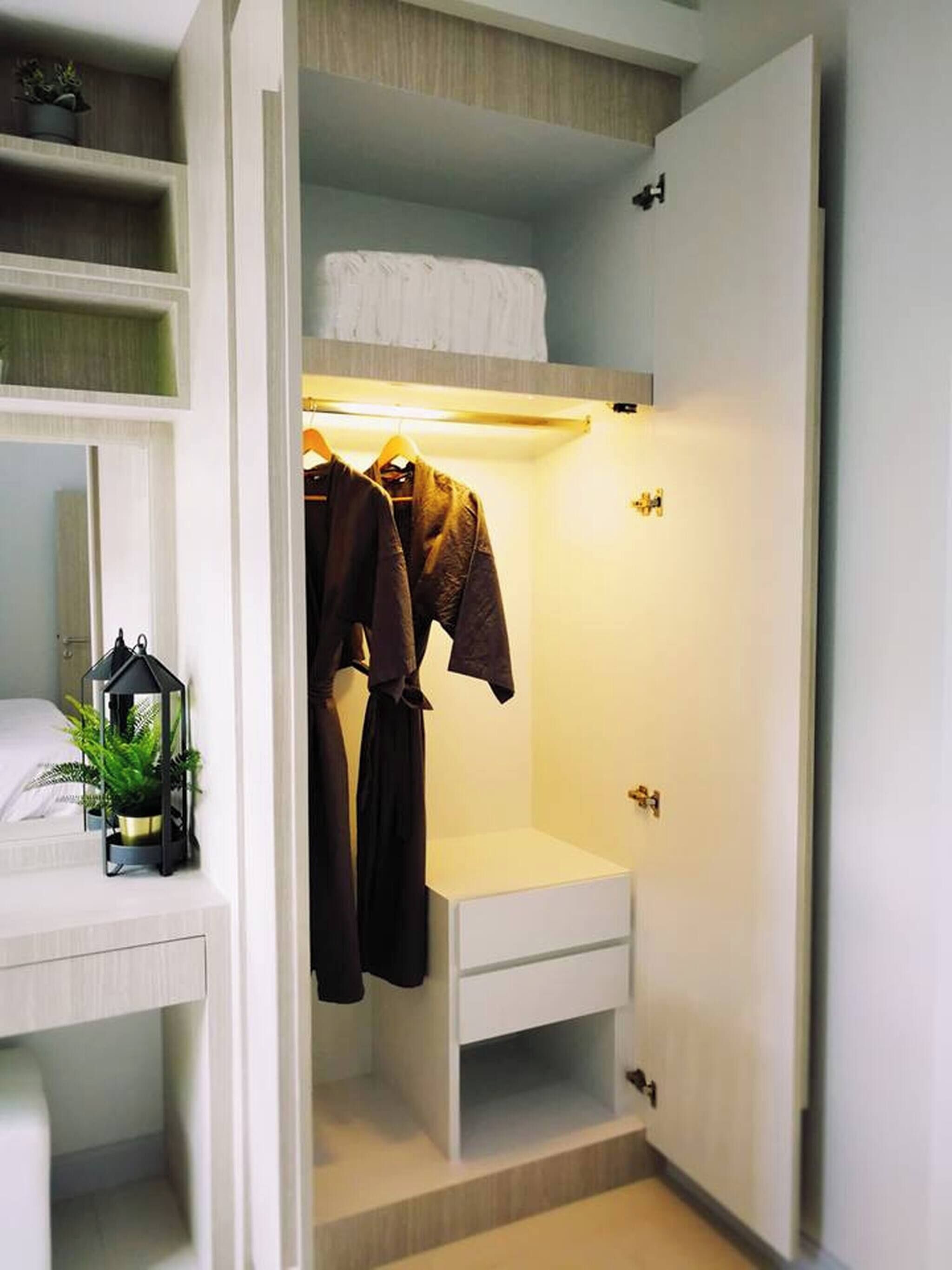 A walk-in closet with a bed, a small table, and a hanging robe rack.