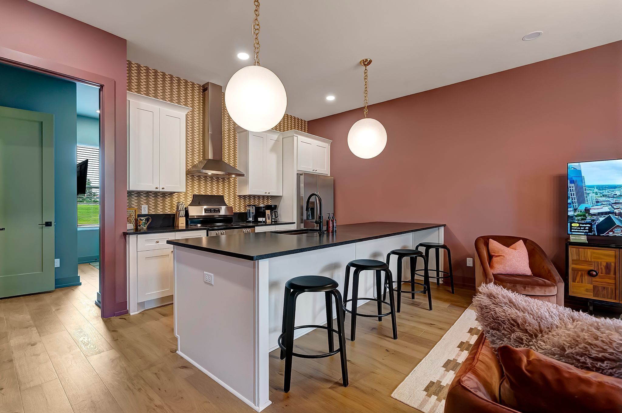 A modern kitchen with a central island, bar stools, and a large TV.