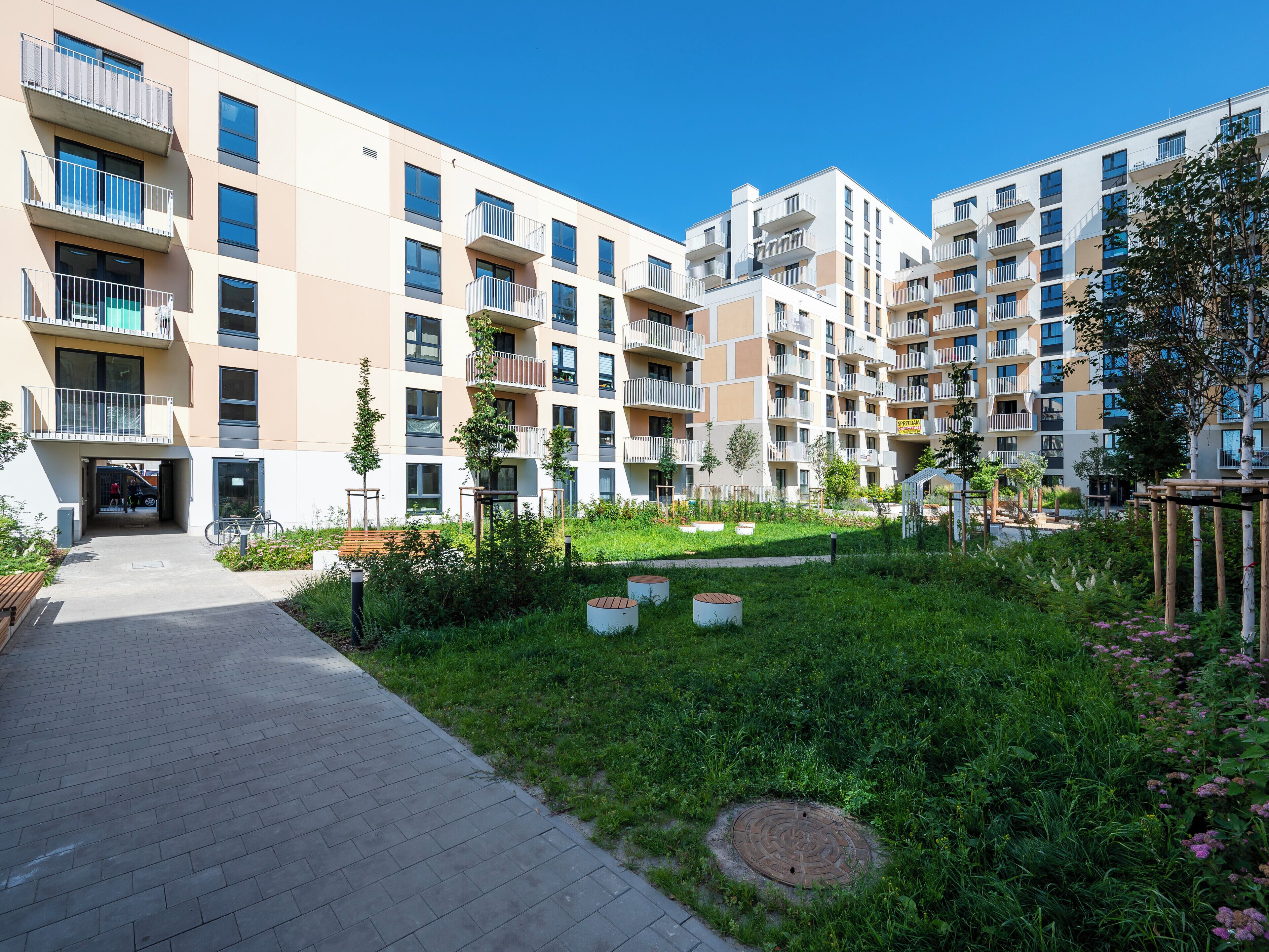 Un moderno edificio residenziale con cortile interno, balconi e una passeggiata lastricata.