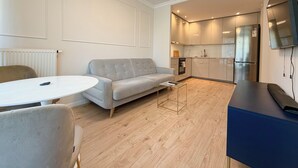 Uma sala de estar moderna com um sofá, uma mesa redonda e uma televisão.