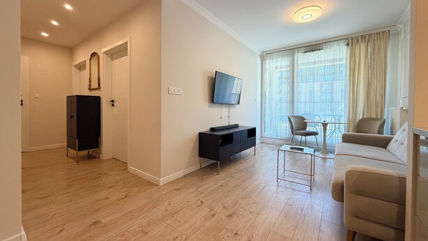 Uma sala de estar moderna com um sofá, TV e uma área de jantar com mesa e cadeiras.