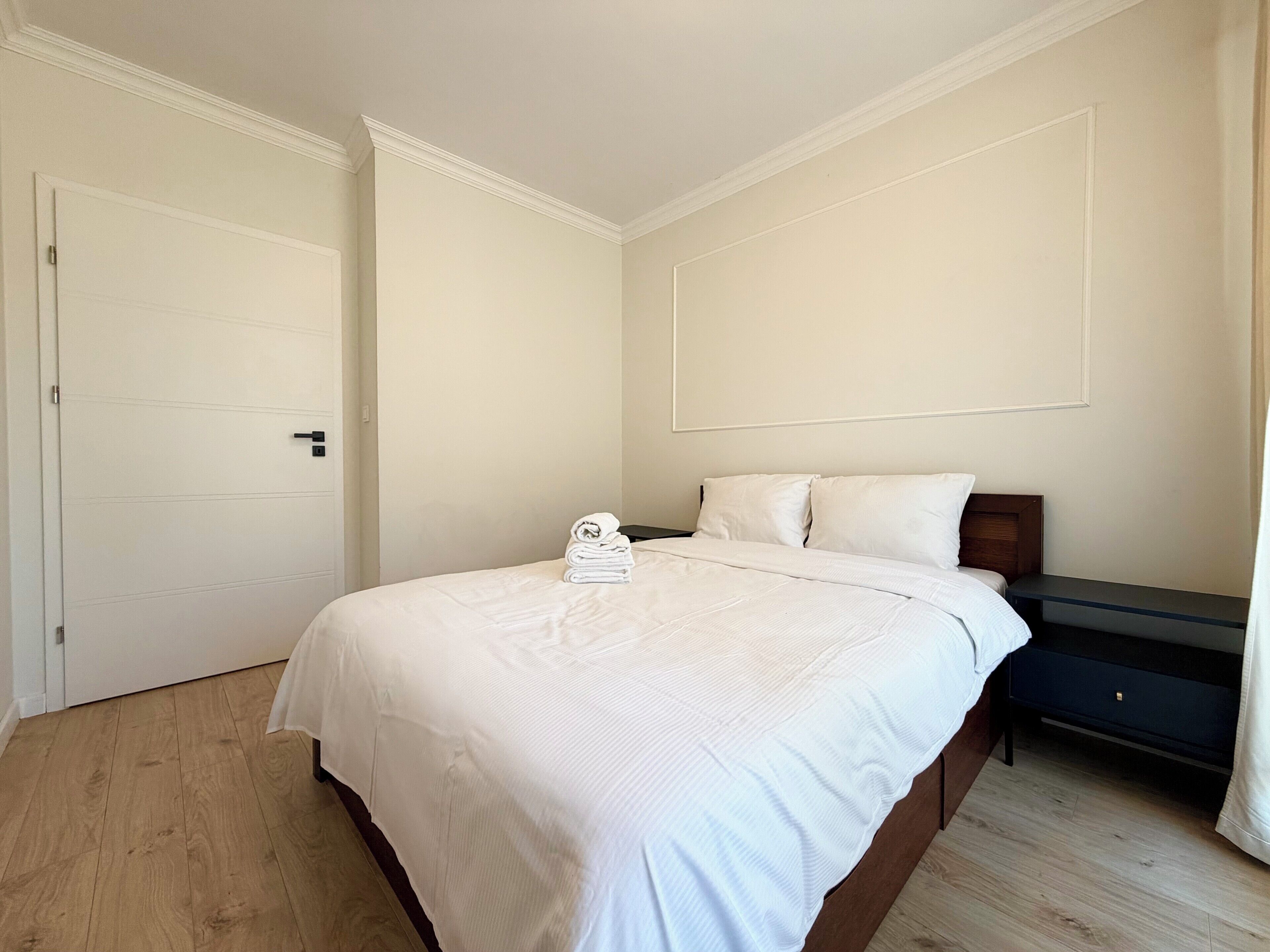 Une chambre à coucher avec un lit, une table de chevet, une porte et un plancher en bois.