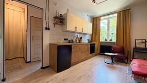 Eine moderne Küche mit Holzschränken, einem eingebauten Geschirrspüler und einem Fenster mit Vorhängen.