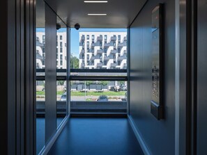 An elevator interior with a view of modern buildings outside. - Kopcińskiego Deluxe Studio ( Łódź)