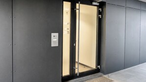 Ein moderner Aufzug mit Glastür, Bedienfeld und Metallgriff.