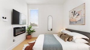 Ein modernes Schlafzimmer mit Bett, Fernseher, Topfpflanze und Kunstwerk.