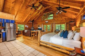 Eine Hütte mit Küche, Essbereich und einem großen Bett mit vielen Kissen.