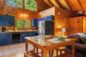 Ein Holzblockhaus-Innenraum mit Küche, Essbereich und einer Couch.