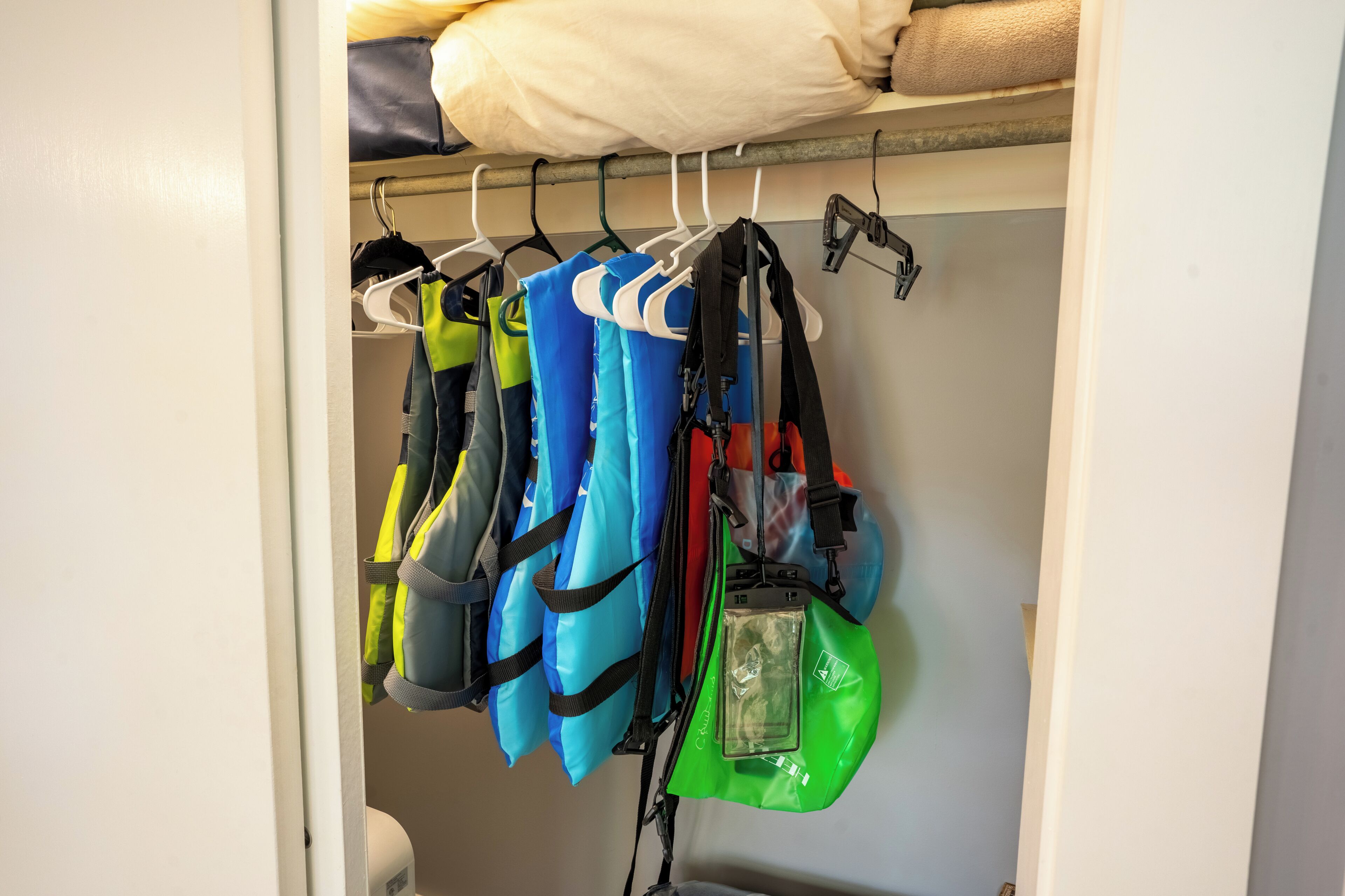 Um armário com vários cabides pendurando bolsas e uma mala.