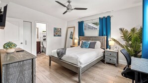 Una camera da letto con un letto, un comodino, una lampada, una sedia e una ventola a soffitto.
