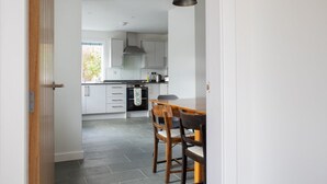 A modern kitchen with white cabinets, a black countertop, and a wooden dining table with chairs.