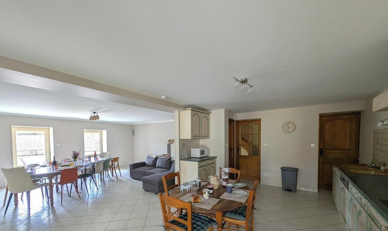 A spacious living area with a dining table, sofa, and kitchen area.