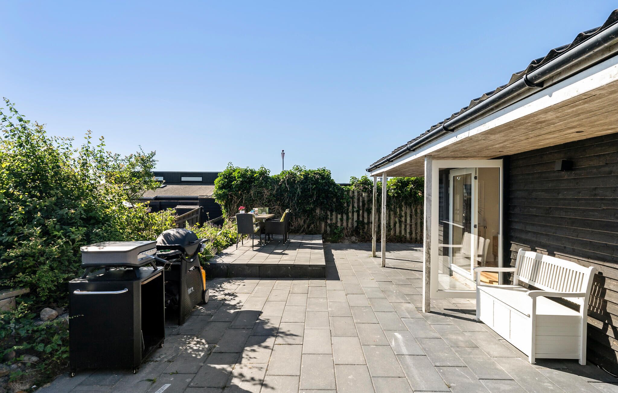 Un espace patio équipé d’un barbecue, de meubles de jardin et d’une clôture en bois.