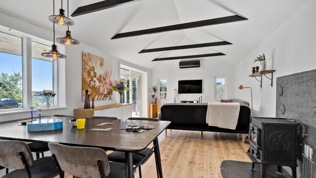 A modern living space with a dining area, sofa, TV, and a fireplace. - Awesome home in Munkebo with house sea view (Munkebo)
