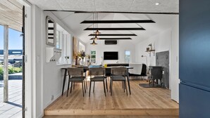 A modern kitchen with a dining area, wooden flooring, and a large window. - Awesome home in Munkebo with house sea view (Munkebo)