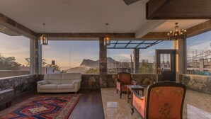 A spacious living area with a large window, a sofa, a chair, and a patterned rug.