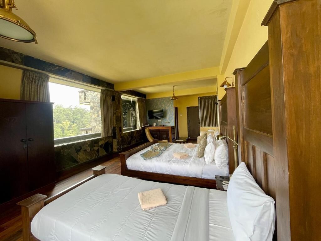 Habitación de hotel con dos camas, un armario de madera, una televisión y una ventana con vistas.