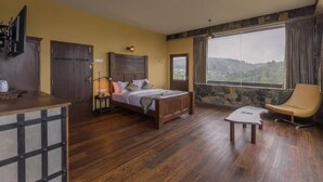 A bedroom with a bed, a desk, a chair, and a large window with a view.
