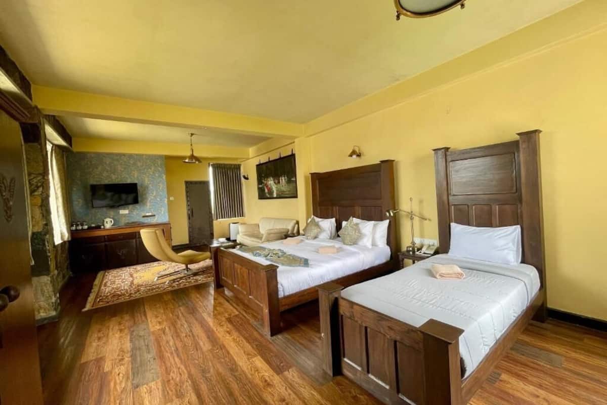 Una habitación de hotel con dos camas de madera, un escritorio, una silla y un televisor.