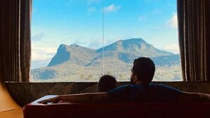 A room with a large window, a red sofa, and a view of a mountain.