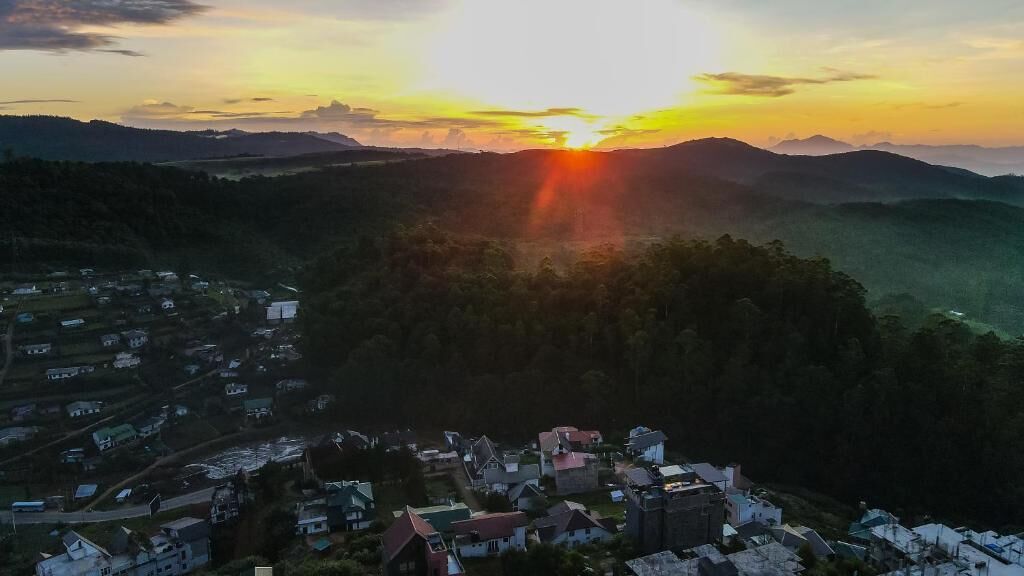 A mountainous landscape with a village at sunset.