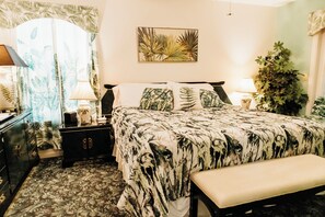 Una camera da letto con un letto, comodini, una panca, una cassettiera, una lampada e una pianta.