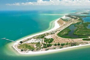 An aerial view of a coastal area with a beach, a marina, and a road leading to a peninsula with buildings and greenery. -  Three Palms 3BR / sleeps 8 / beach 5 min. / backs to nature trail & park w/lake (Largo)
