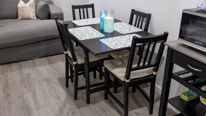 Een eettafel met vier stoelen, een kaars en placematen.