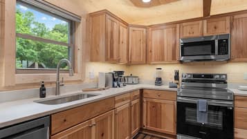 A modern kitchen with wooden cabinets, stainless steel appliances, and a large window.