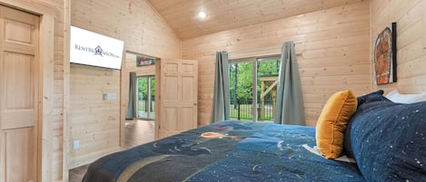 Ein Schlafzimmer einer Holzhütte mit Bett, Deckenventilator und Blick ins Freie.