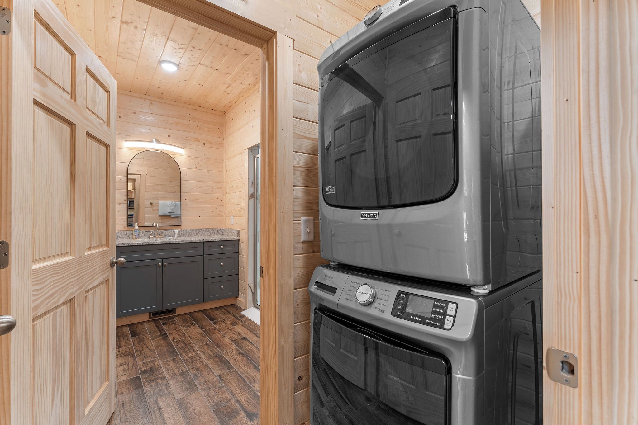 A compact kitchen with a built-in oven and microwave, wooden walls, and a small countertop.