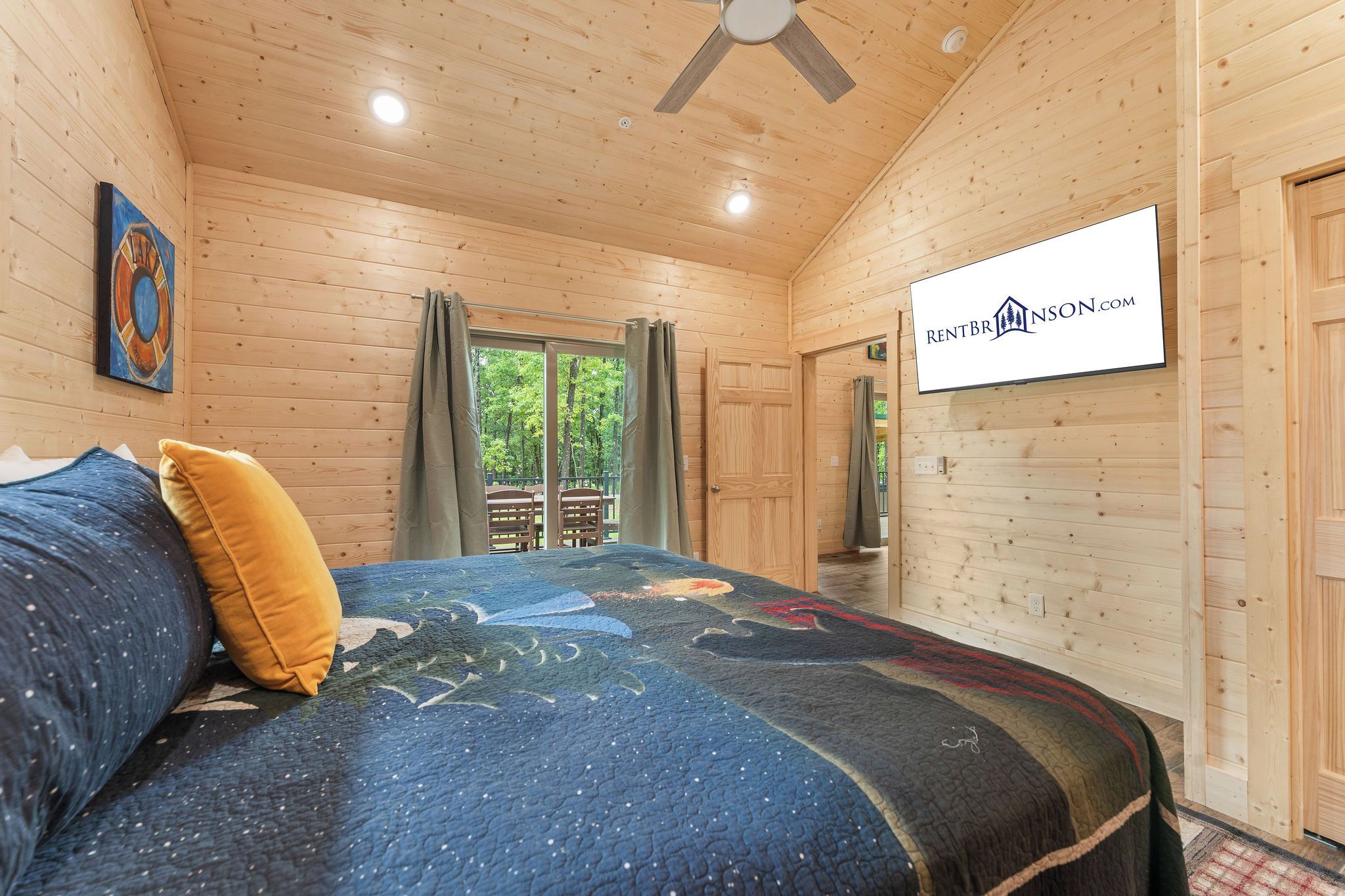 A bedroom with a bed, a ceiling fan, a window with curtains, and a sign on the wall.