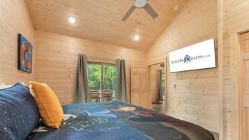 A bedroom with a bed, a ceiling fan, a window with curtains, and a sign on the wall.