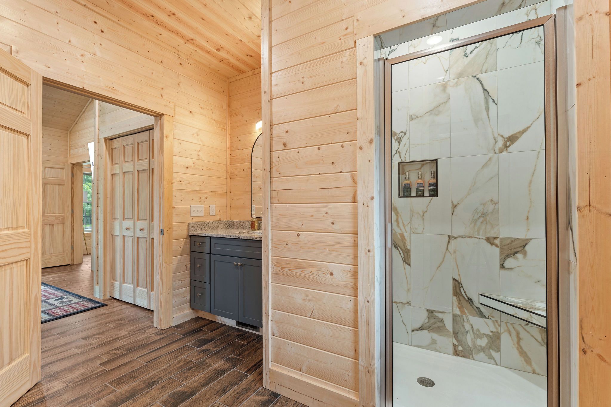 Een houten interieur met een badkamer, voorzien van marmeren tegels en een douchecabine.