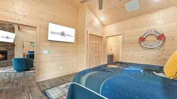 A wooden cabin interior with a bed, a fireplace, a ceiling fan, and a sign for RentBrinson.com.