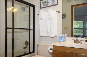 A bathroom with a glass-enclosed shower, a toilet paper holder, and a sink with a mirror. - 2-bedroom townhome in pleasant Pinetop Country Club with AC (Pinetop Country Club)