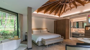 Un dormitorio moderno con una cama grande, una zona de estar, una bañera y un comedor.