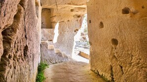 A narrow passageway with natural rock formations and a staircase leading to an outdoor area. - Apartment in Ricadi (048) (Ricadi)