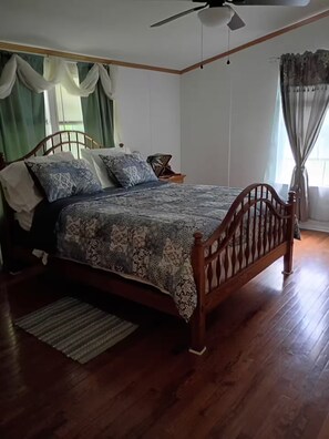A bedroom with a wooden bed, a nightstand, a ceiling fan, and a window with curtains. - Private 1-BR Ensuite with Separate Entrance I 5min DT Jonesborough (Jonesborough)