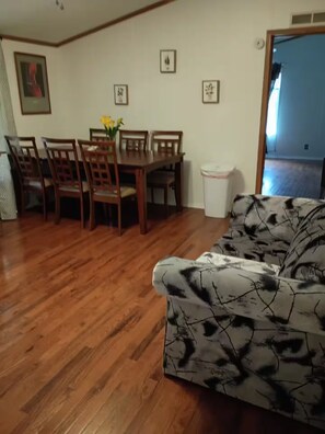A dining area with a wooden table and chairs, a sofa, and framed pictures on the wall. - Private 1-BR Ensuite with Separate Entrance I 5min DT Jonesborough (Jonesborough)