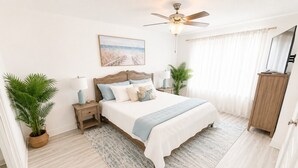A bedroom with a bed, bedside tables, a ceiling fan, a painting, and a potted plant. - Quick Drive to Beach | Sleeps 6 (Santa Rosa Beach)