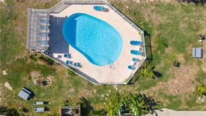 Una piscina octagonal amb una terrassa al voltant, cadiretes i un edifici petit.