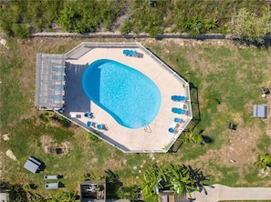 An octagonal pool with a surrounding deck, lounge chairs, and a small building. - Cozy 1-bedroom condo in soothing Port Aransas with AC (Port Aransas)