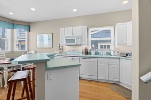 Una cocina moderna con armarios blancos, una isla central y un comedor con sillas de madera.