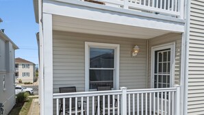 Een huis met twee verdiepingen, een overdekte veranda, een raam met luiken en een witte balustrade.