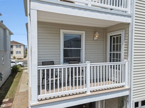A two-story house with a covered porch, a window with blinds, and a white railing. - Family-Friendly 3BR/2BA OCNJ Getaway with Parking, Patios & Outdoor Shower (Ocean City)